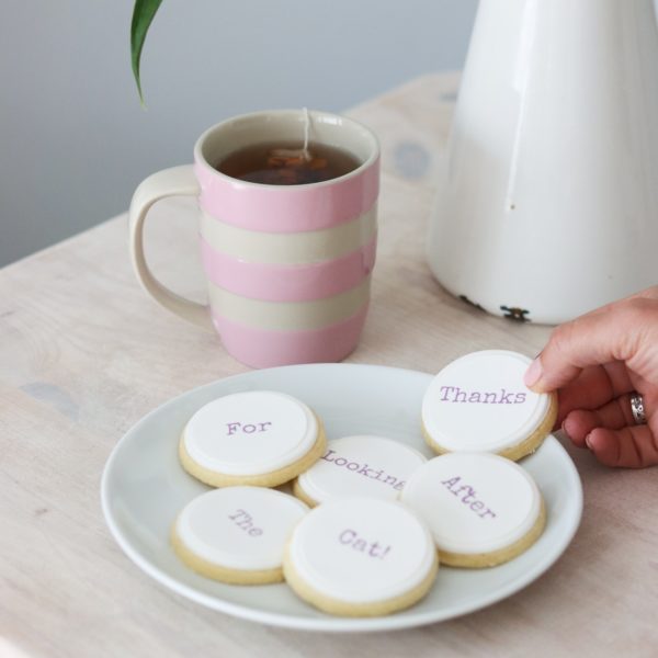 Shortbread biscuits on a white plate with a personalised message printed in edible ink. A pink mug in the background